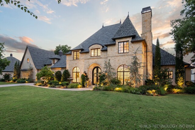 french country inspired facade with a yard