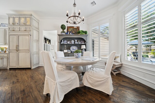 dining room with crown molding, dark wood-type flooring, and an inviting chandelier