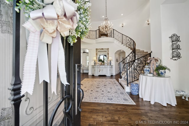 foyer featuring dark hardwood / wood-style floors, a towering ceiling, and a notable chandelier