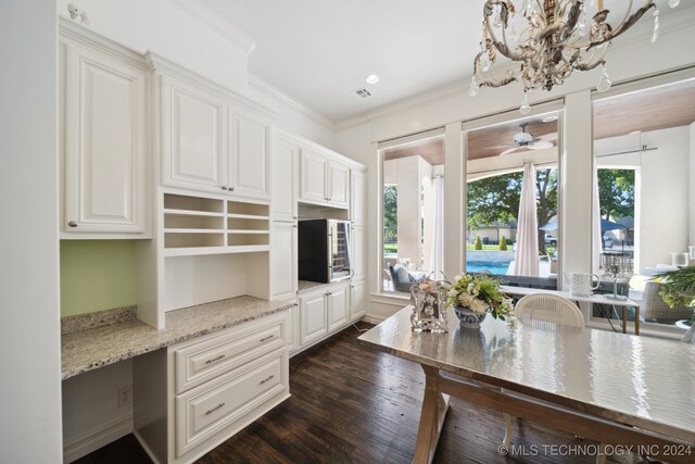 interior space featuring dark wood-type flooring, built in desk, white cabinetry, light stone countertops, and crown molding