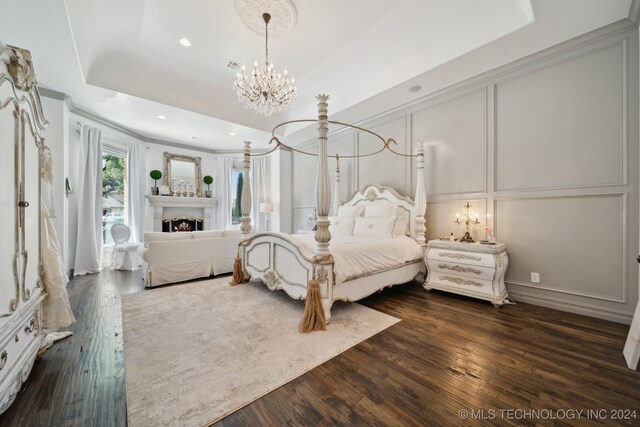 bedroom with dark hardwood / wood-style floors, a chandelier, and a raised ceiling