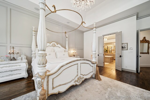 bedroom with hardwood / wood-style flooring, connected bathroom, and a notable chandelier