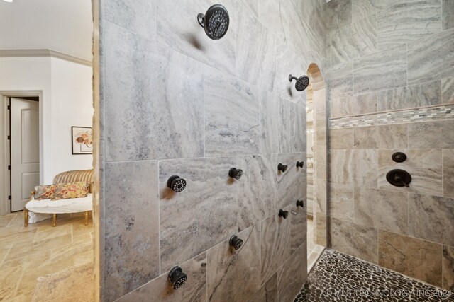 bathroom featuring tiled shower and crown molding