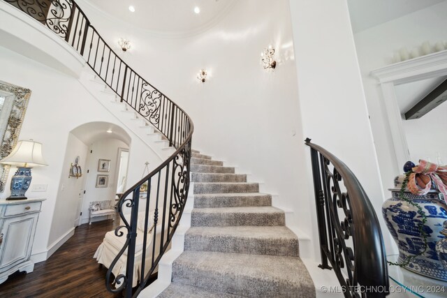 stairway featuring a towering ceiling and hardwood / wood-style flooring