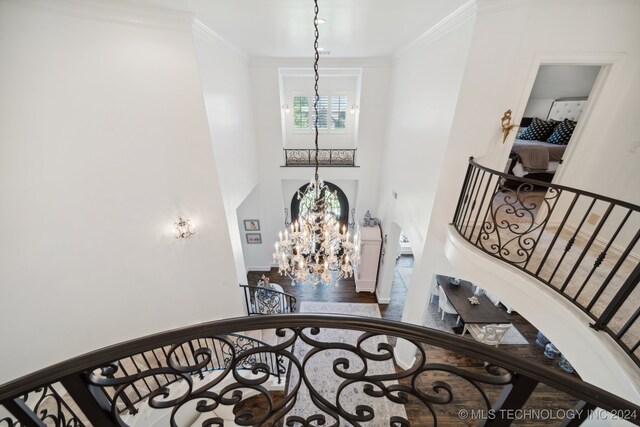 stairway with a notable chandelier, crown molding, and a high ceiling