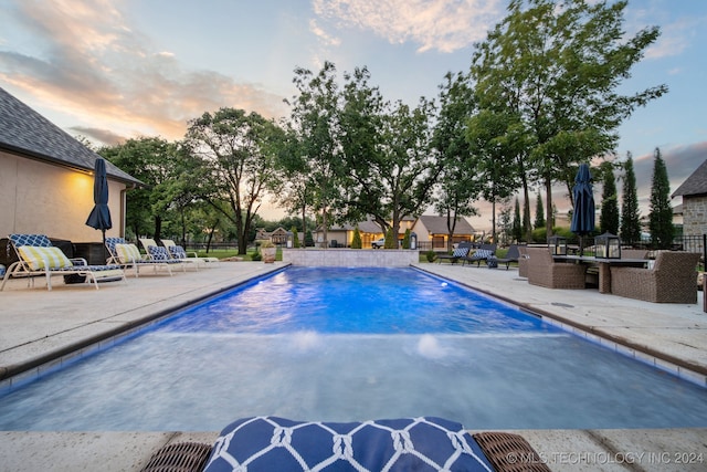 pool at dusk with a patio area