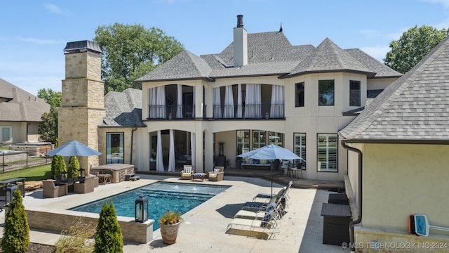 back of property with a balcony and a patio