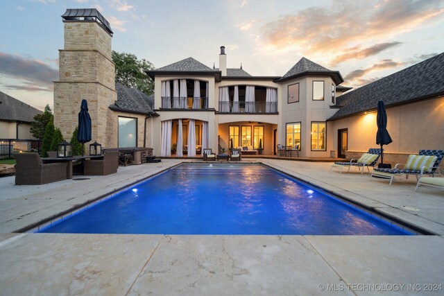 pool at dusk featuring a patio and french doors