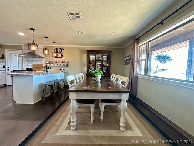 dining room with hardwood / wood-style floors, crown molding, and a textured ceiling