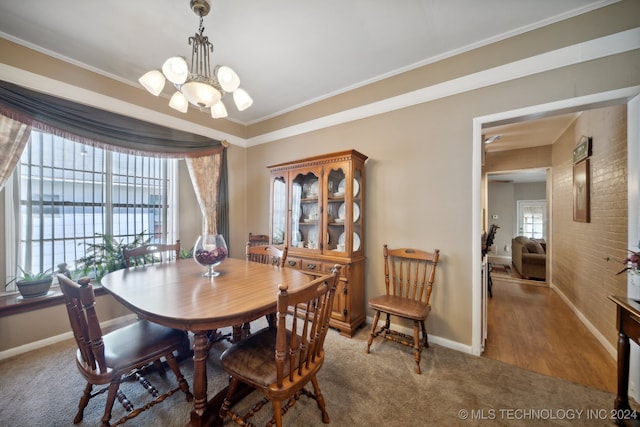 carpeted dining room featuring crown molding, brick wall, and a notable chandelier