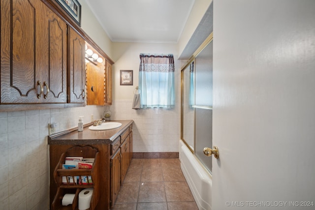 bathroom with tile walls, vanity, tile patterned floors, and shower / bath combination with glass door