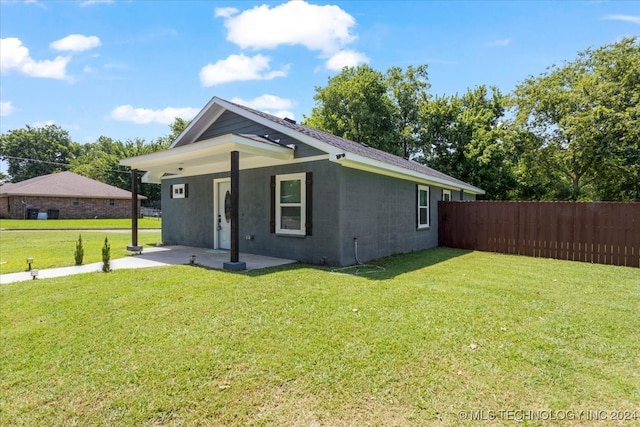 view of side of home featuring a patio and a lawn