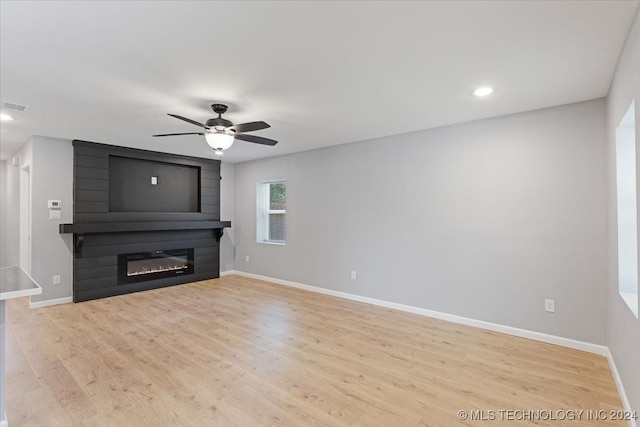 unfurnished living room featuring ceiling fan, light hardwood / wood-style flooring, and a fireplace