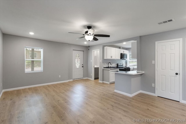 kitchen featuring a wealth of natural light, light hardwood / wood-style floors, white cabinets, and electric range