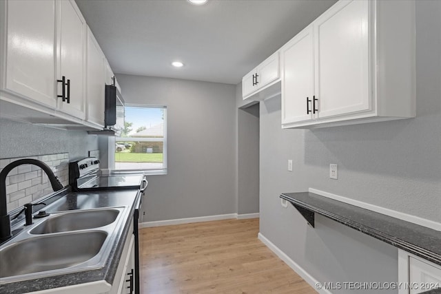 kitchen with light hardwood / wood-style flooring, electric range, tasteful backsplash, white cabinets, and sink