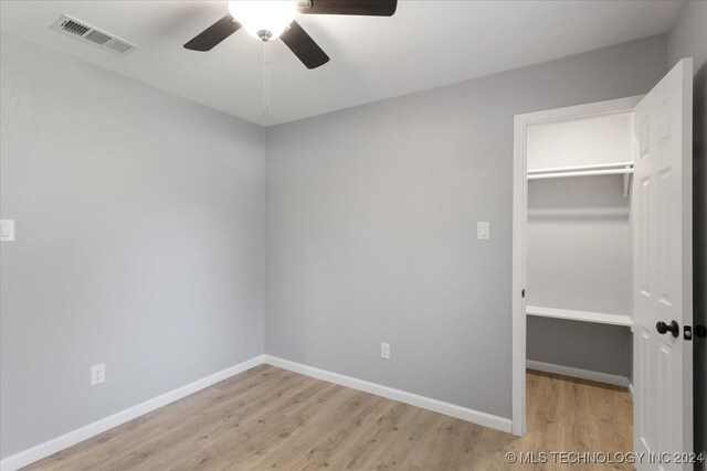 unfurnished bedroom with light hardwood / wood-style floors, a spacious closet, ceiling fan, and a closet