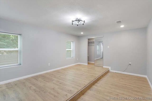 empty room featuring a textured ceiling and light hardwood / wood-style floors