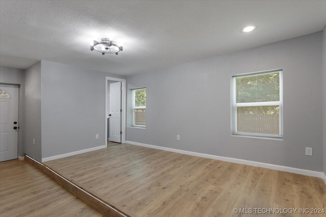 unfurnished room with a textured ceiling and light hardwood / wood-style floors