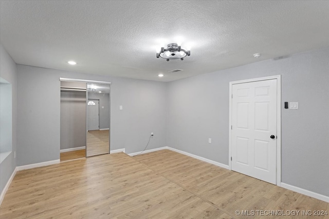 spare room featuring light wood-type flooring and a textured ceiling