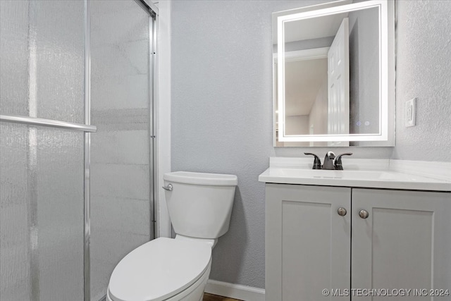 bathroom featuring an enclosed shower, toilet, and vanity