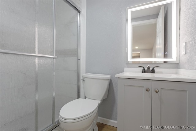 bathroom featuring toilet, vanity, and walk in shower