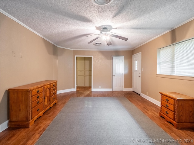 interior space featuring hardwood / wood-style flooring, ceiling fan, ornamental molding, and a textured ceiling