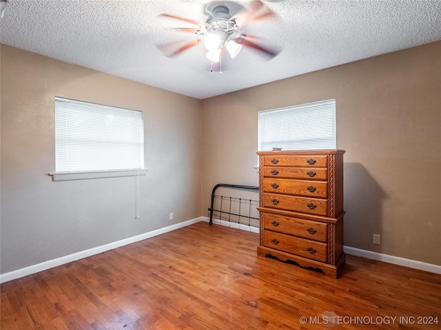 unfurnished bedroom with ceiling fan, hardwood / wood-style floors, and a textured ceiling