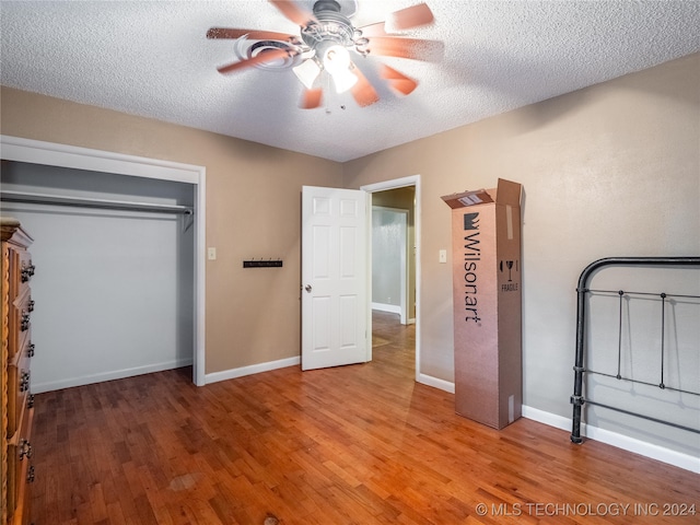 unfurnished bedroom with a closet, ceiling fan, hardwood / wood-style floors, and a textured ceiling