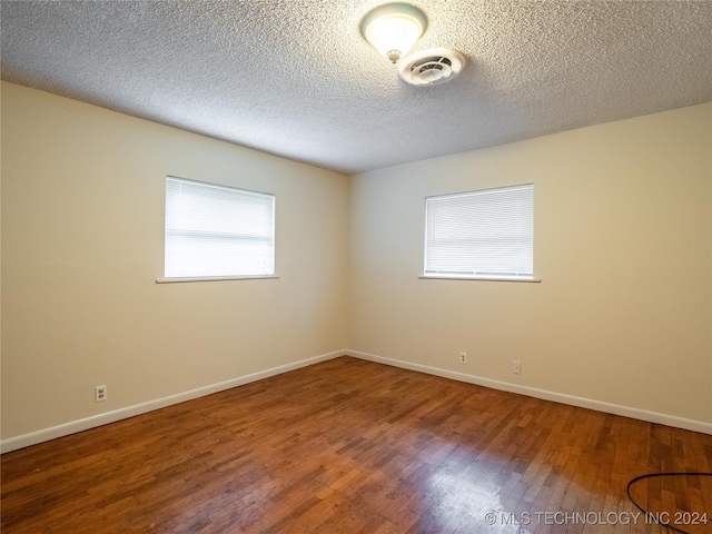 empty room featuring wood-type flooring and a textured ceiling