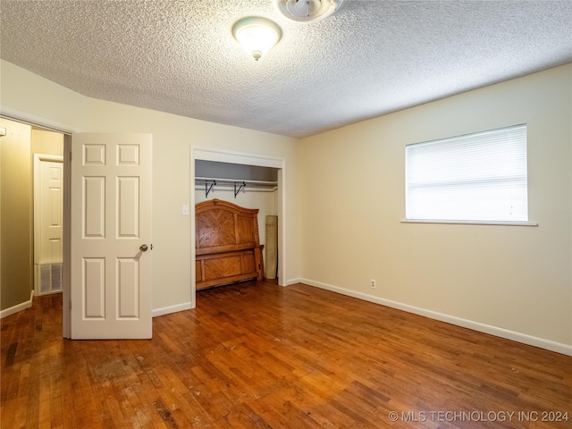 unfurnished bedroom featuring wood-type flooring, a textured ceiling, and a closet