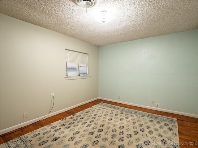 spare room with wood-type flooring and a textured ceiling