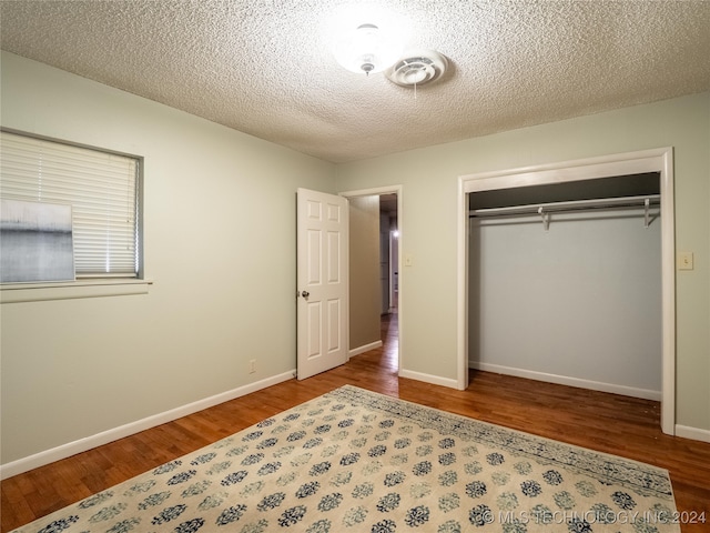 unfurnished bedroom featuring a textured ceiling, hardwood / wood-style flooring, and a closet