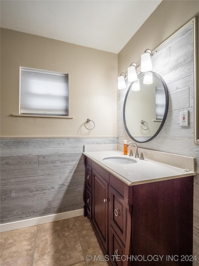 bathroom with tile patterned flooring, vanity, and wood walls