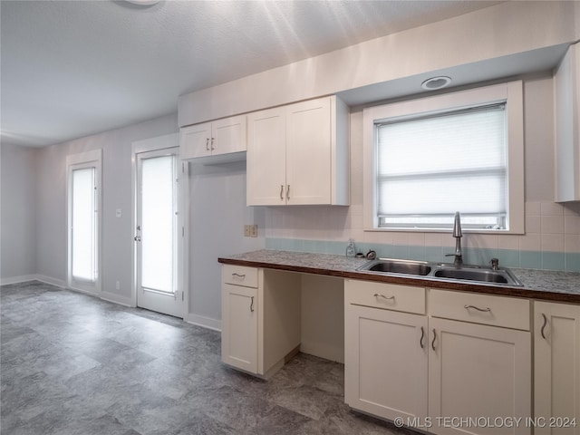 kitchen featuring decorative backsplash, sink, and white cabinets