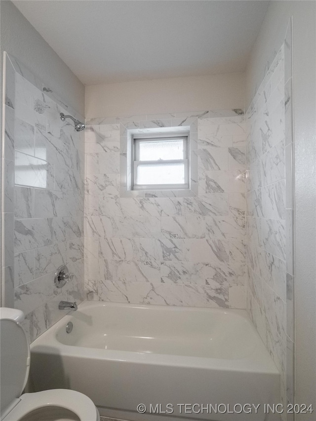 bathroom featuring toilet and tiled shower / bath