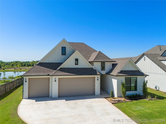 view of front facade featuring a front lawn, a garage, and a water view