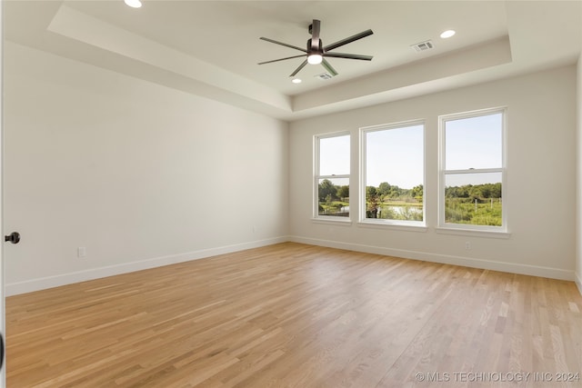 spare room with ceiling fan, a raised ceiling, and light hardwood / wood-style floors