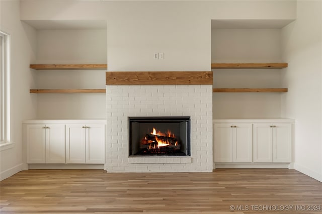 unfurnished living room featuring light hardwood / wood-style floors and a brick fireplace