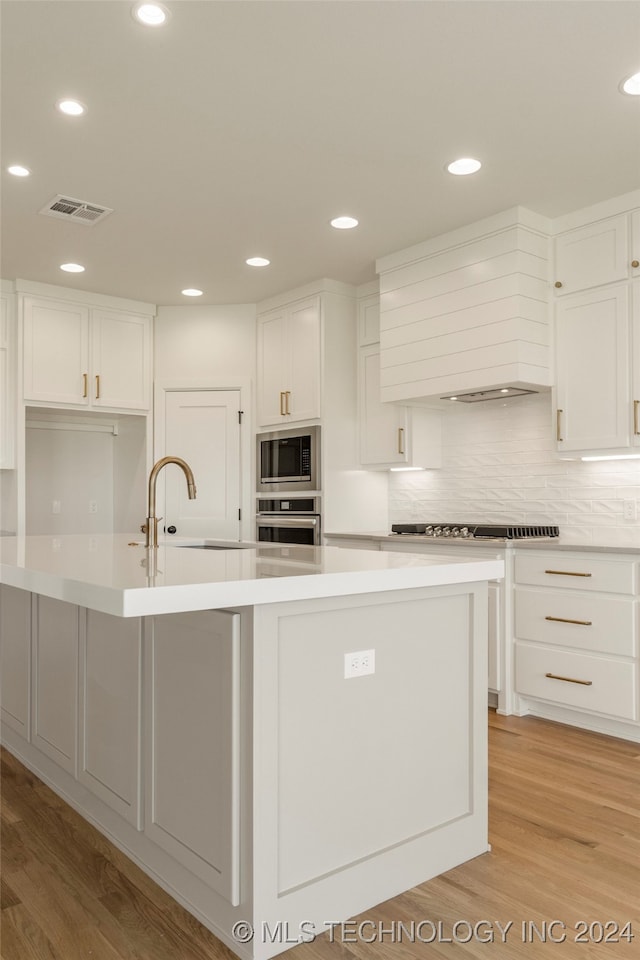 kitchen featuring stainless steel appliances, light hardwood / wood-style flooring, decorative backsplash, sink, and white cabinets