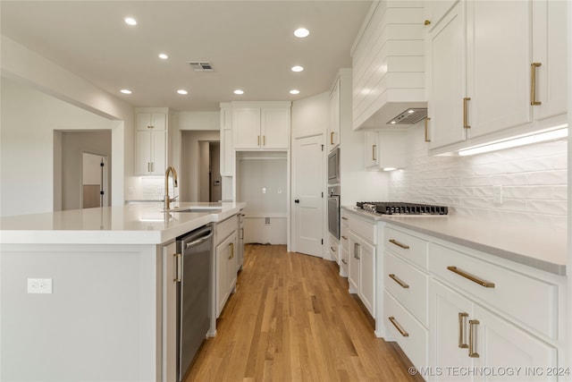 kitchen featuring sink, custom range hood, light hardwood / wood-style flooring, white cabinetry, and stainless steel appliances