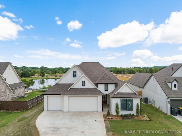 view of front of home with a front lawn, a garage, and a water view