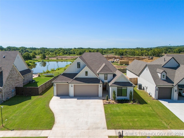 view of front of property with a garage, a front yard, and a water view