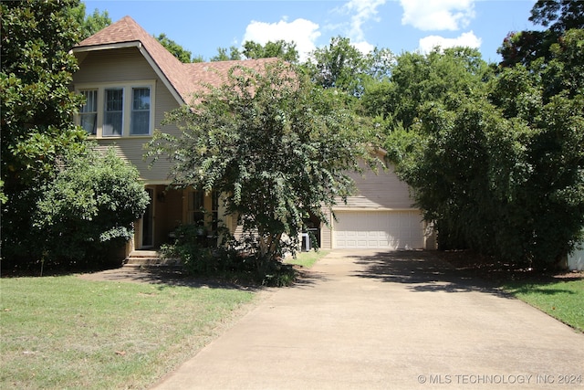 view of property hidden behind natural elements with a garage and a front lawn