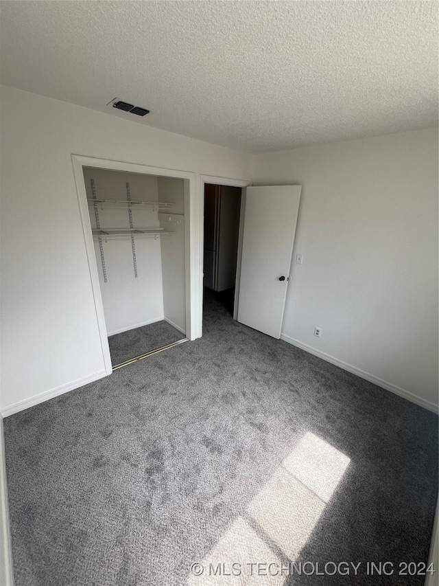 unfurnished bedroom featuring carpet flooring, a textured ceiling, and a closet