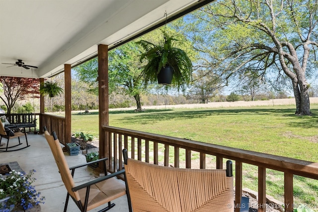 wooden terrace with a lawn and ceiling fan