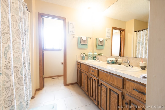 bathroom with tile patterned flooring, a textured ceiling, and dual bowl vanity