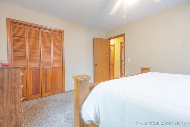 carpeted bedroom with ceiling fan, a closet, and a textured ceiling