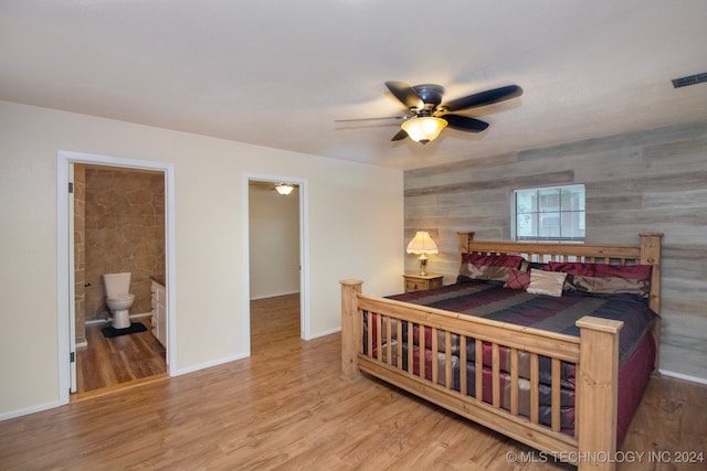 bedroom featuring a ceiling fan, baseboards, wood finished floors, ensuite bathroom, and visible vents