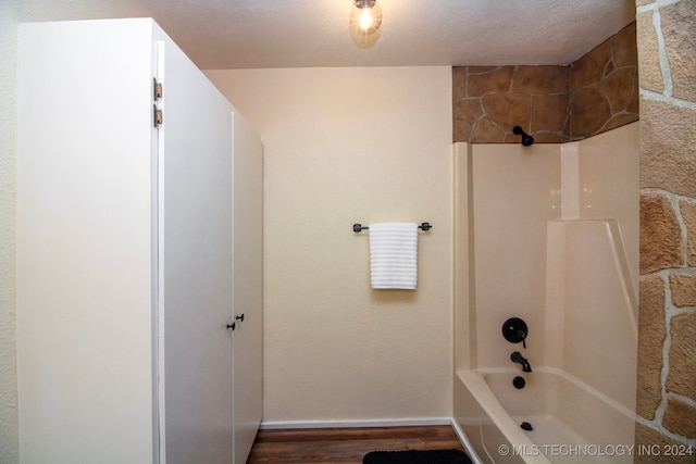 bathroom with hardwood / wood-style flooring, a textured ceiling, and shower / washtub combination