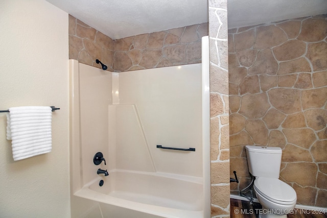 bathroom featuring toilet, a textured ceiling,  shower combination, and tile walls